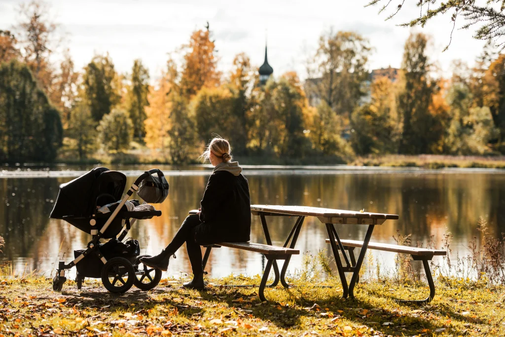 En person som sitter ned en vagn på hösten vid vatten.