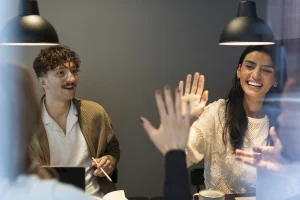 Fyra personer som sitter mitt emot varandra vid ett bord. Två är på väg att göra high five.